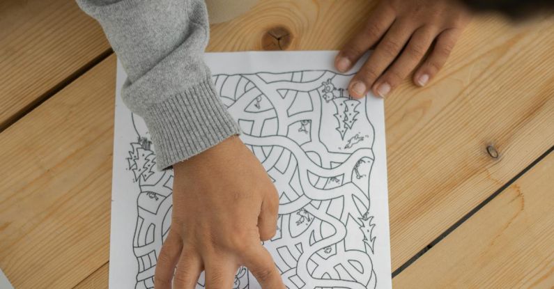 Brain Puzzle - From above of crop anonymous child sitting on floor and solving maze during weekend at home