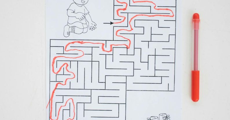 Brain Puzzle - Top view of solved labyrinth test with little boy and boots painted on paper placed on white desk with red pen