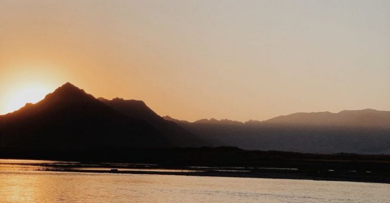 Sunrise Checklist - A bird flying over the water at sunset