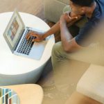 Laptop Home - Man Using Gray Laptop While Sitting on Beige Sofa