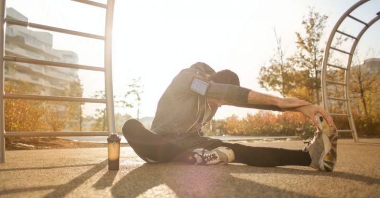 Runner Sunset - Flexible sportsman stretching on sports ground