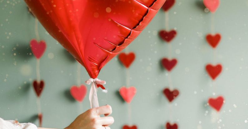 Heart Shopfront - A person holding a red heart shaped balloon in front of a wall of hearts