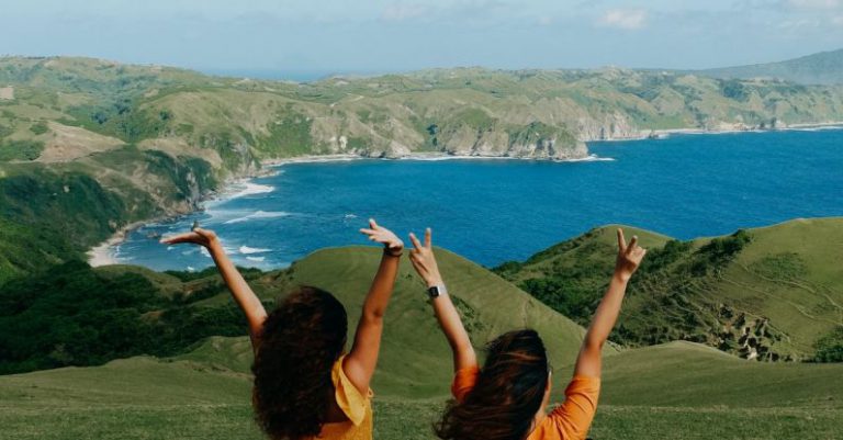 Wallet Freedom - Two women sitting on a hill with their arms up